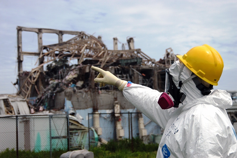 An IAEA inspector in protective equipment examines the Fukushima Reactor Unit 3 to assess tsunami damage